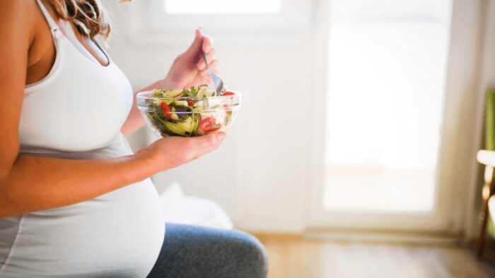 Beautiful pregnant woman eating healthy food and salads