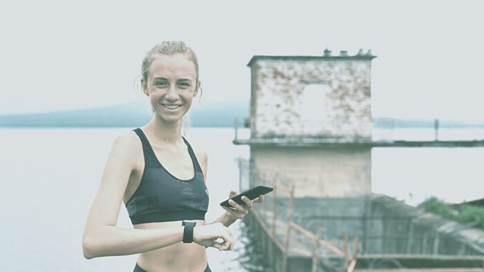 Skinny woman with smart phone and watch exercising outdoor