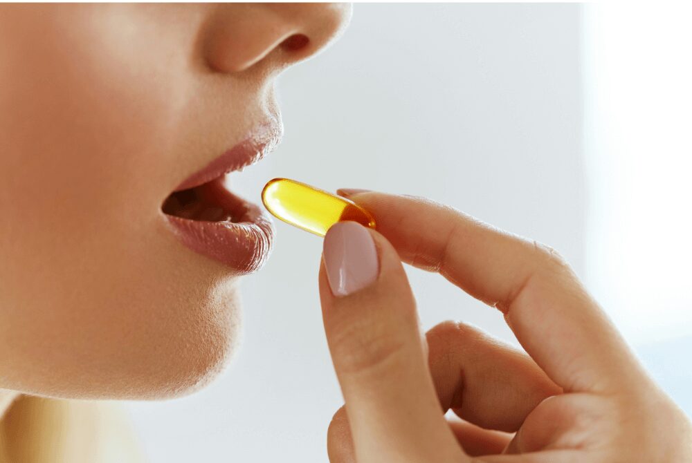 A woman taking a supp capsule for her health, looking determined to benefit from its nutritional properties. 