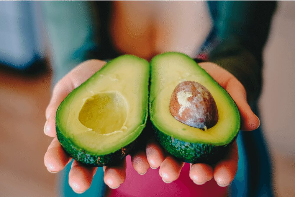 woman holding an avocado split open