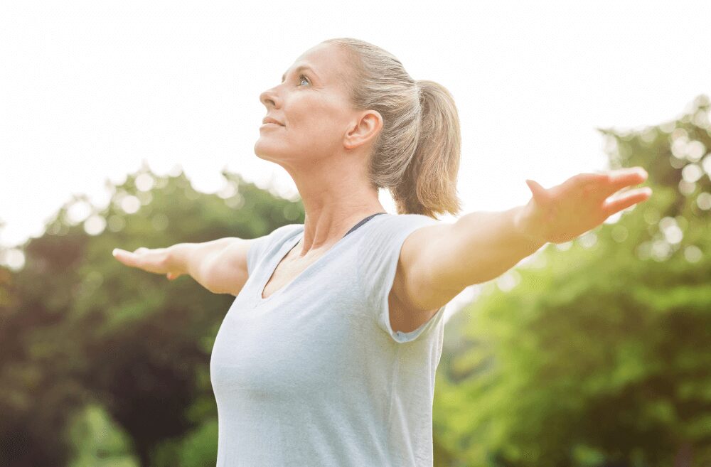 woman over 50 doing yoga pose outside