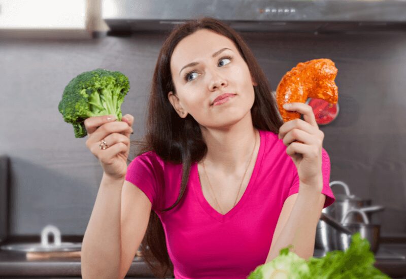 woman deciding between low carb foods - broccoli and chicken