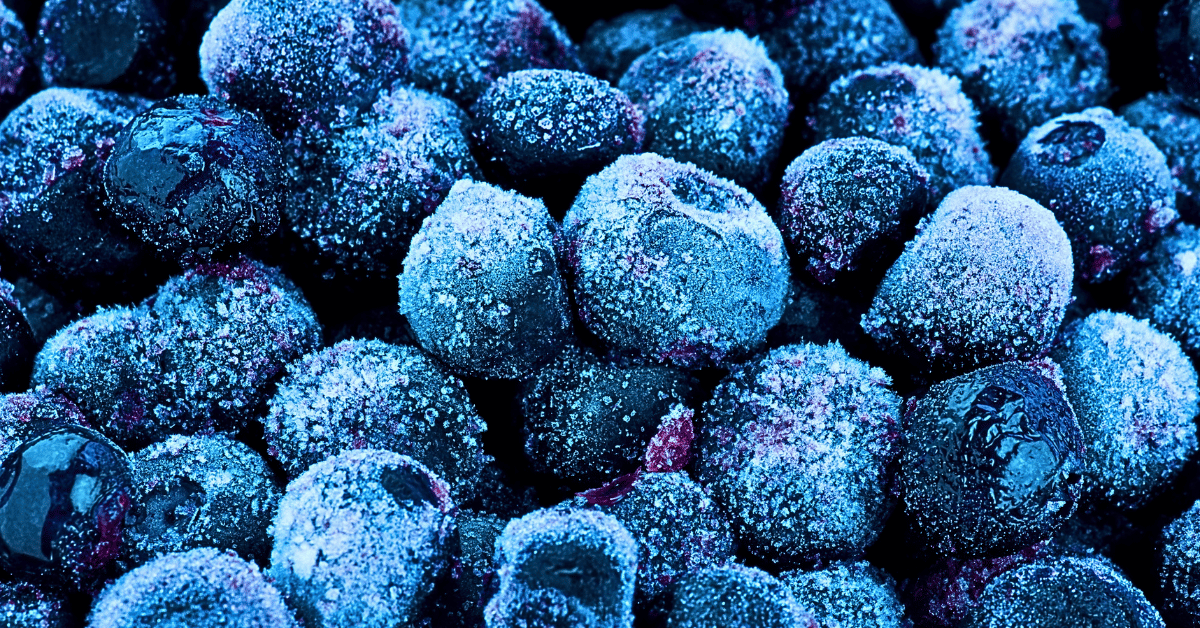 An immersive, up-close visual of frozen blueberries, showcasing their vibrant indigo hue and delicate, frost-kissed texture