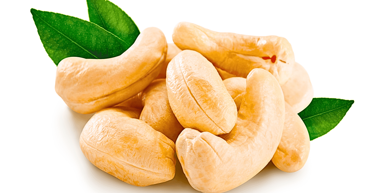 A close-up view of 8 cashews arranged in a circular pattern with a vibrant green leaf placed on top, set against a clean white background.