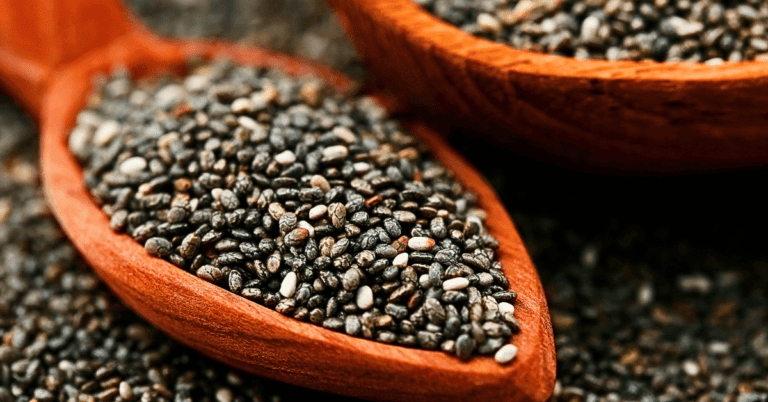 A close-up view of nutrient-rich chia seeds delicately cradled on a wooden spoon, showcasing their tiny, oval-shaped form and distinctive texture.