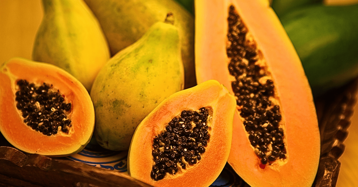 A collection of whole papayas, showcasing their vibrant, golden skin and unique form, with three halves strategically displayed to reveal the luscious, orange flesh and dark seeds up close. 