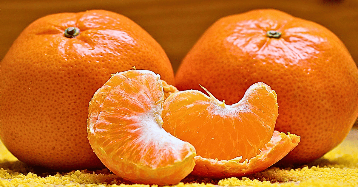 An up-close view of two whole tangerines complemented by artfully arranged slices, presented against a vibrant yellow cloth.